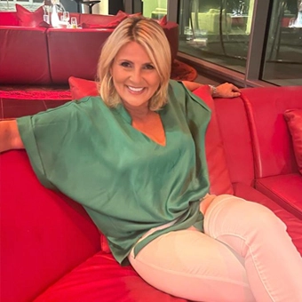 Nadia Schlenkrich smiling while sitting on a red sofa